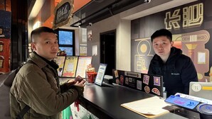 Un mostrador de recepción con una pantalla digital, un código QR y varios adhesivos.