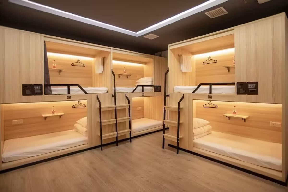A room with three bunk beds, each with a wooden headboard and a small shelf.