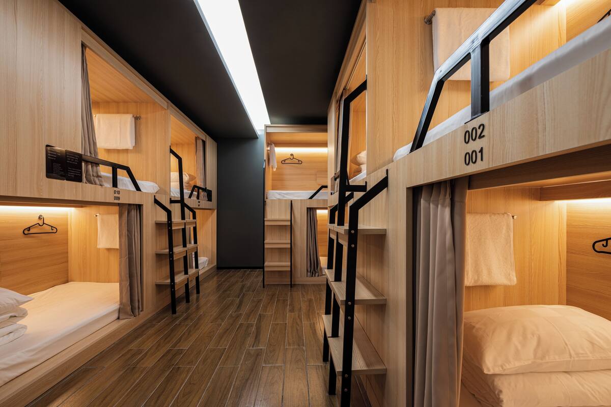 Une chambre d’hôtel compacte avec des lits superposés, des murs en bois et un escalier central.
