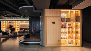 Een modern interieur met een houten vitrine vol gezelschapsspellen en een zithoek met stoelen en een bureau.