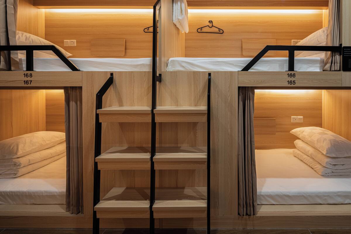 Une chambre avec des lits superposés, des murs en bois et un escalier central.