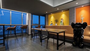 Een moderne eetruimte met een lange tafel en stoelen, een bank en een decoratief beeldhouwwerk.