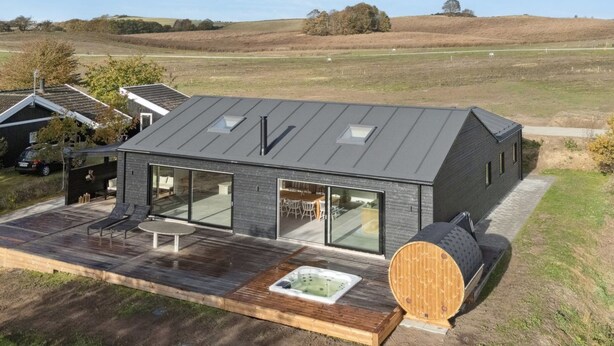 Ein modernes Haus mit einer großen Terrasse, einem Whirlpool und einer Sauna.