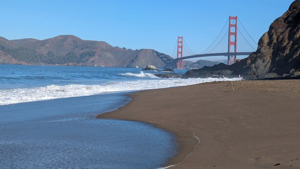Een strand met uitzicht op de Golden Gate Bridge en heuvels op de achtergrond.