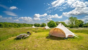 A campsite with several tents, picnic tables, and a grill area.