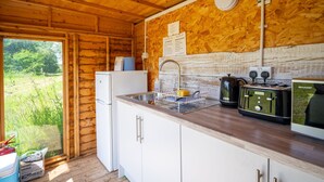 A wooden cabin kitchen with a sink, a refrigerator, a toaster, and a coffee maker.