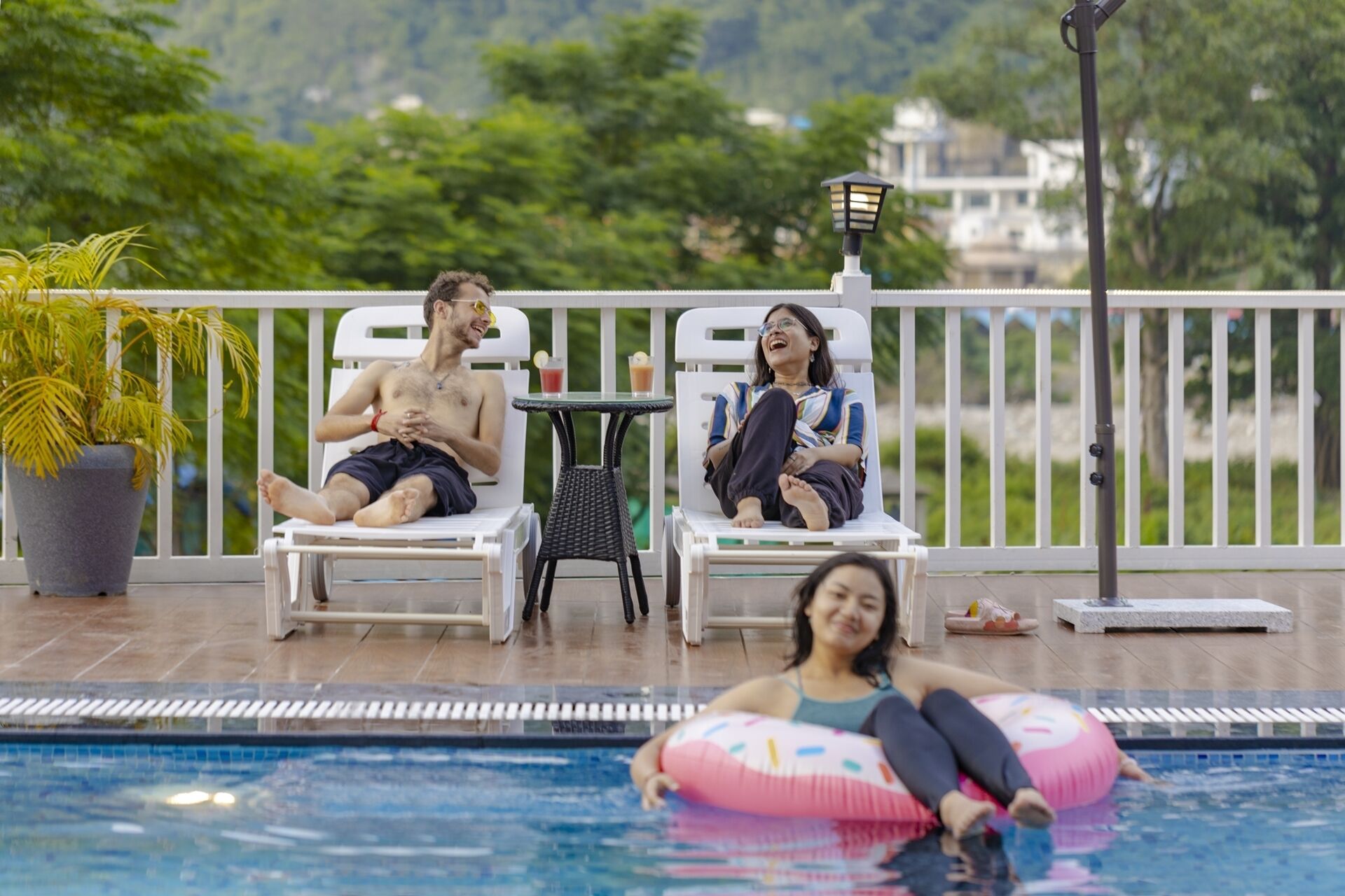 A poolside area with lounge chairs, a small table, and a potted plant.