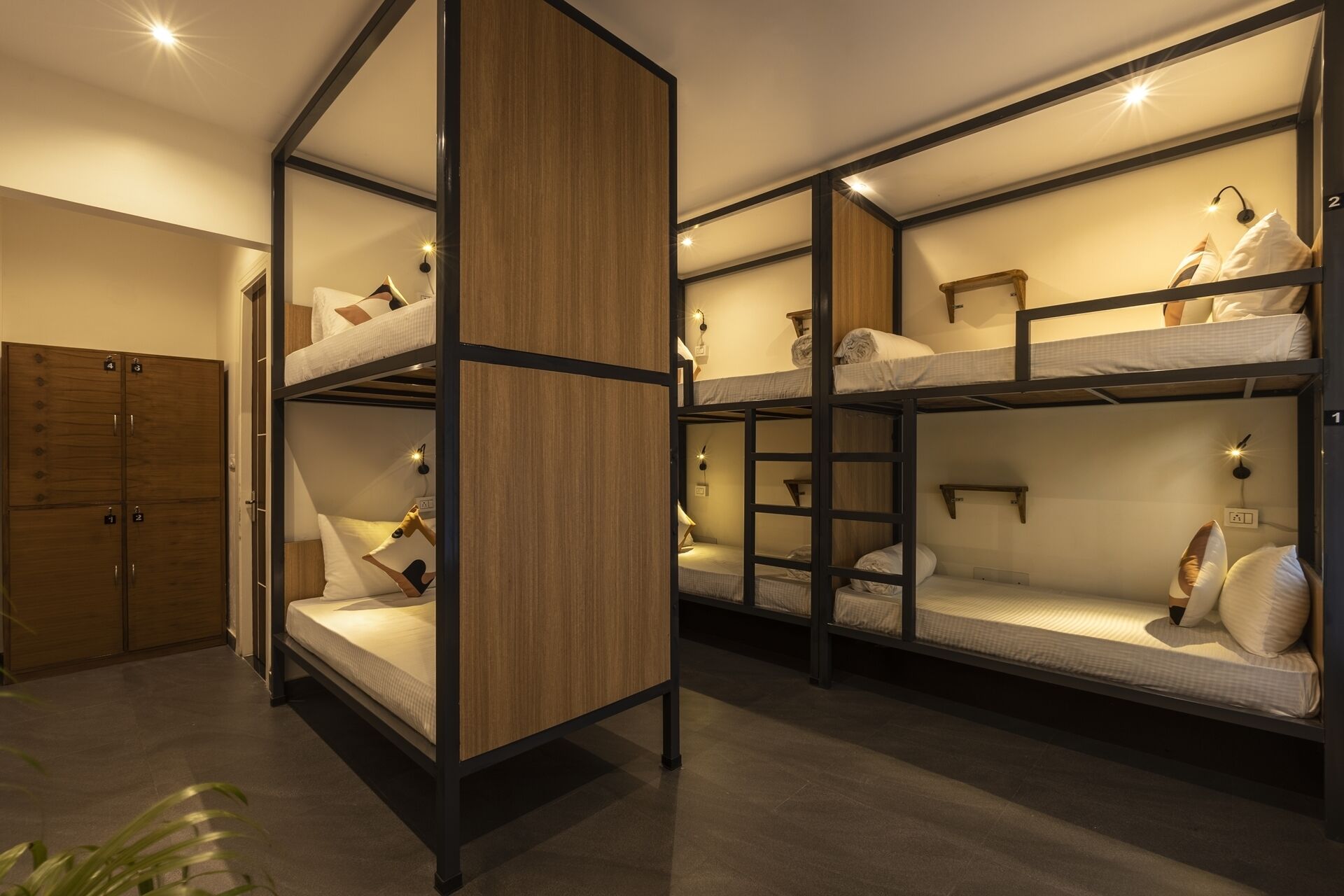 A dormitory room with bunk beds, wooden wardrobe, and bedside lamps.