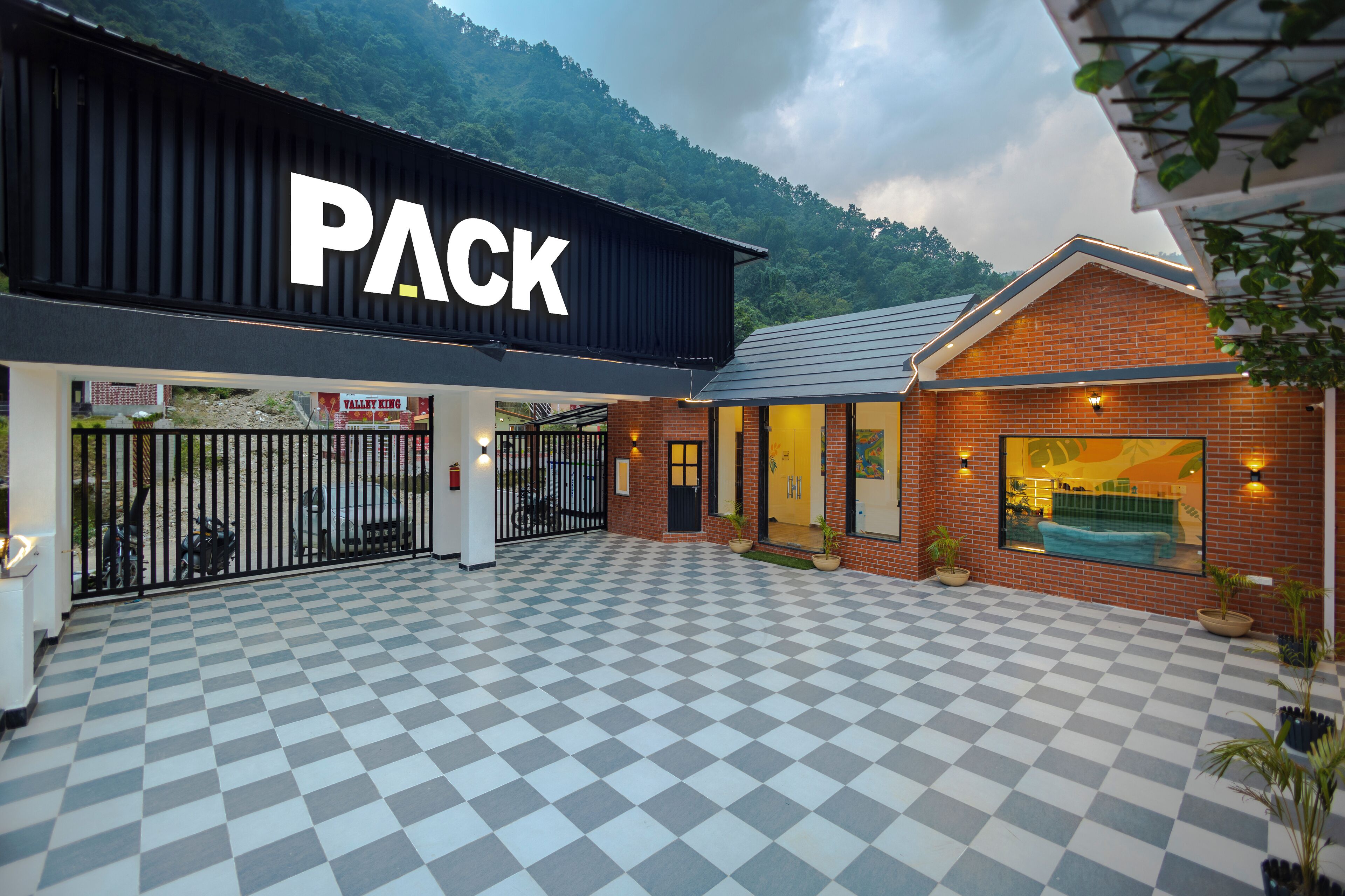 A hotel entrance with a checkered floor, a black sign with the word "PACK", and a mountain backdrop.