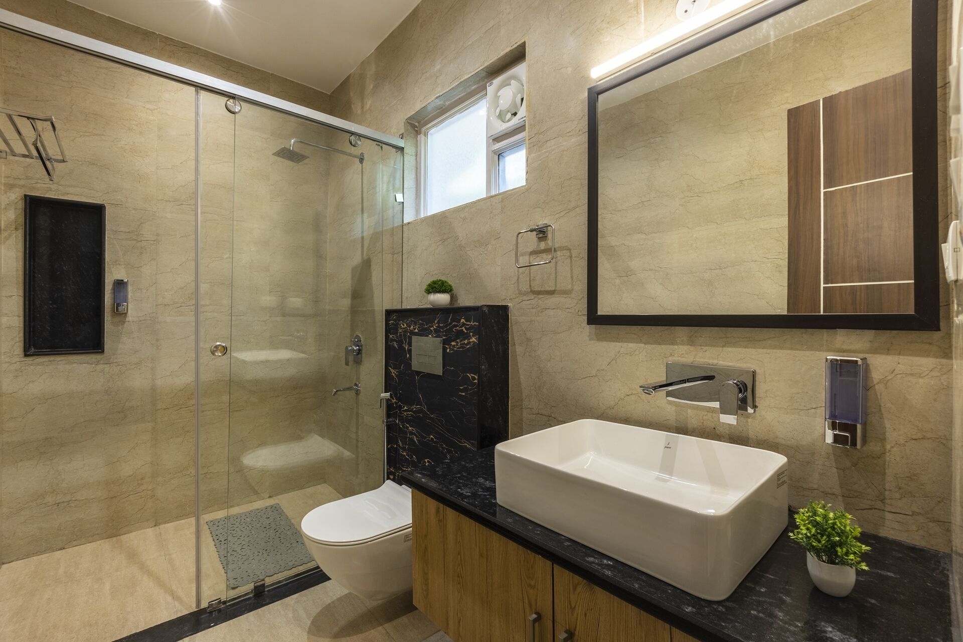 Une salle de bain moderne avec une douche à parois de verre, des toilettes blanches, un meuble-lavabo en marbre noir et un grand miroir.