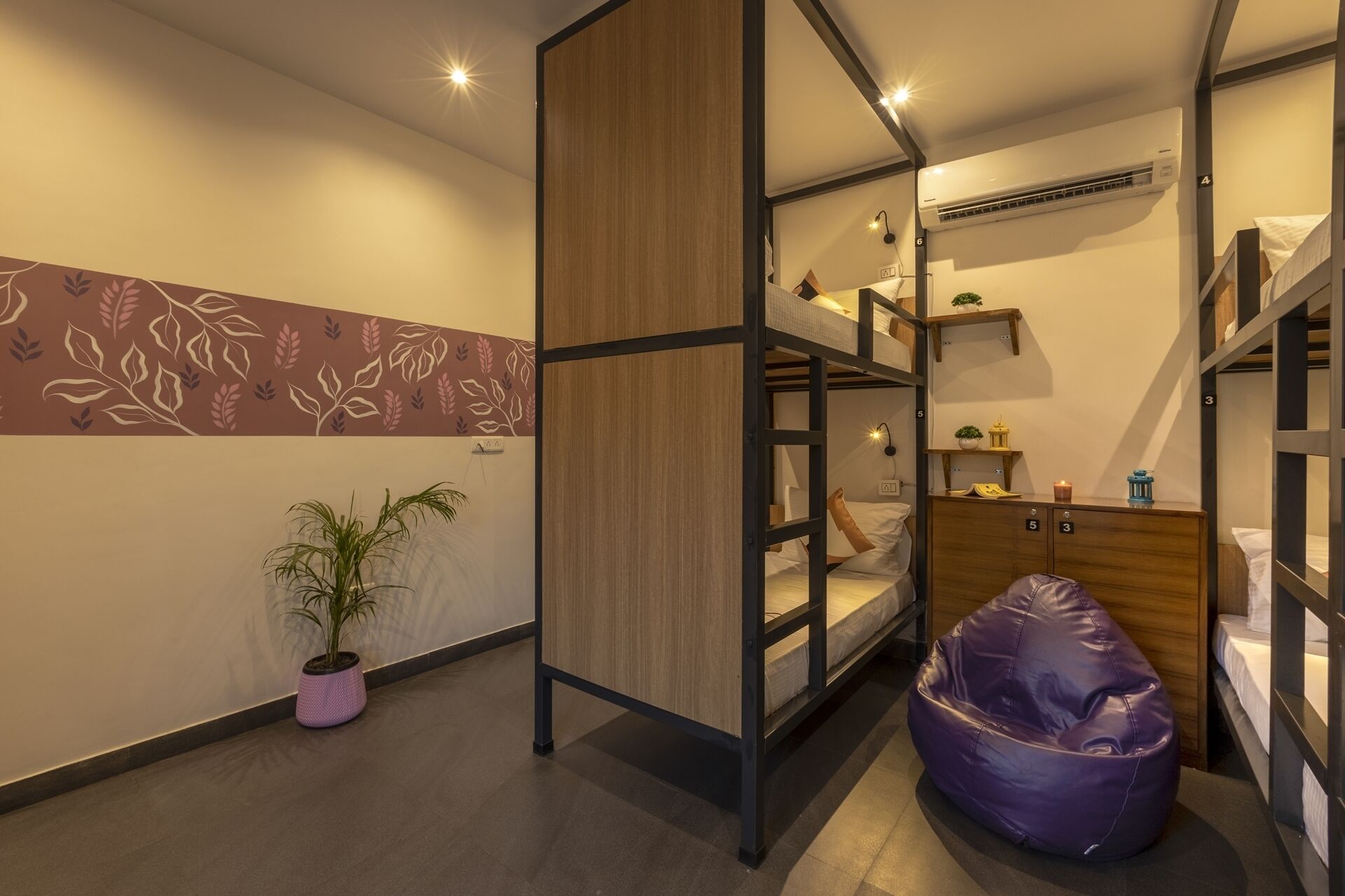 A modern, compact room with bunk beds, a bean bag, and a small plant.