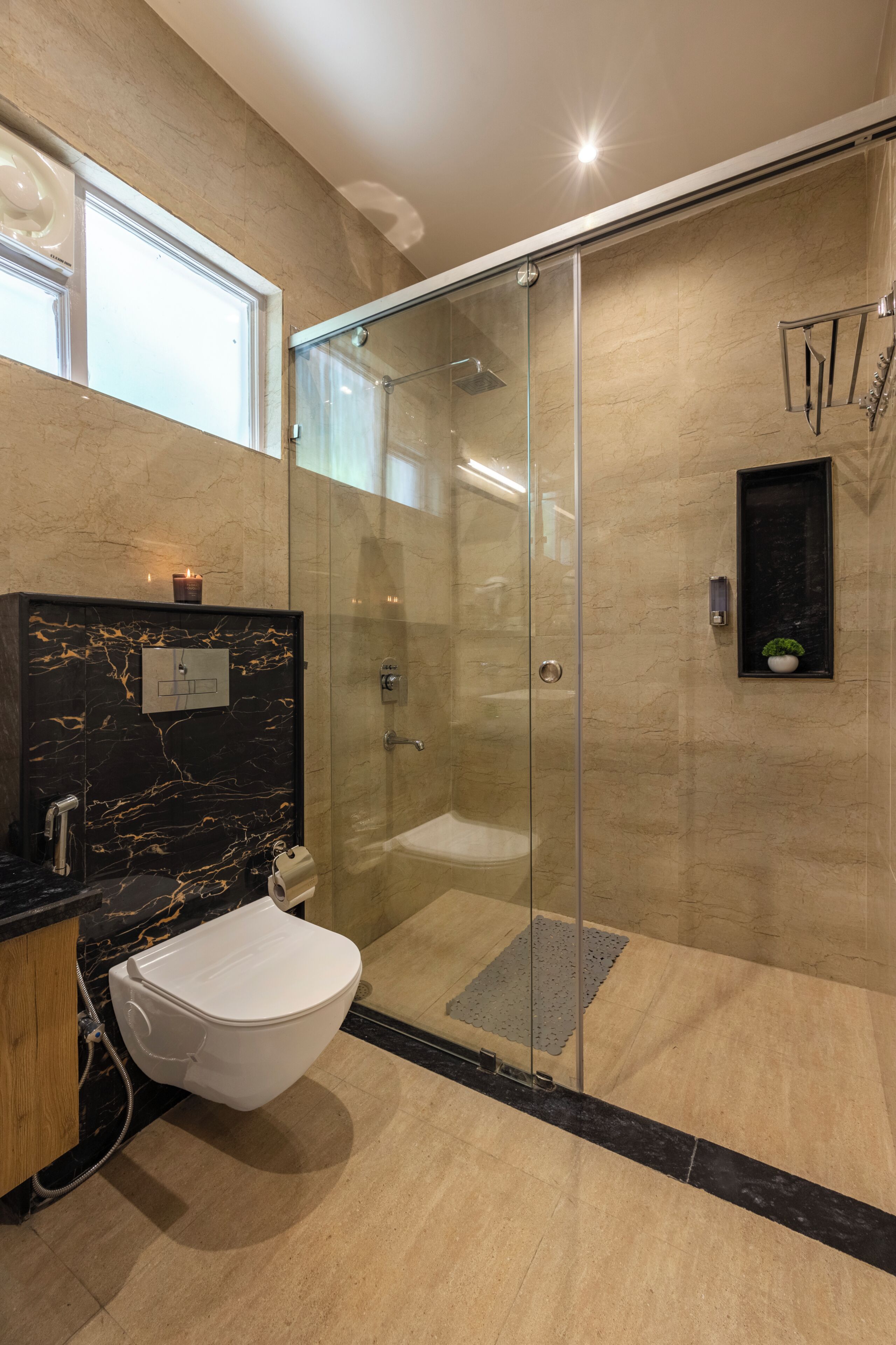 A modern bathroom with a glass-enclosed shower, a white toilet, and a marble vanity.