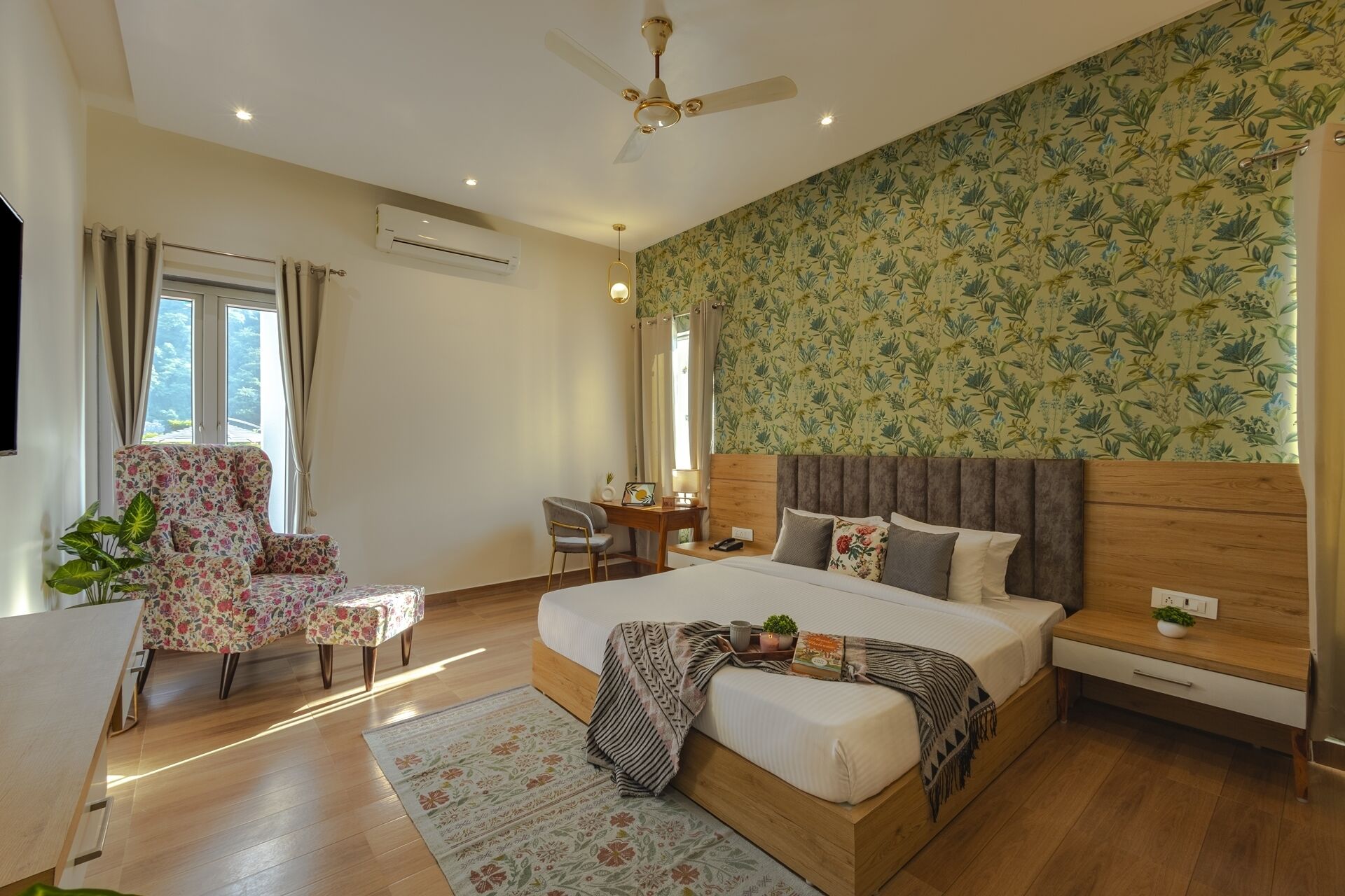 A bedroom with a large bed, a desk, a chair, and a plant.