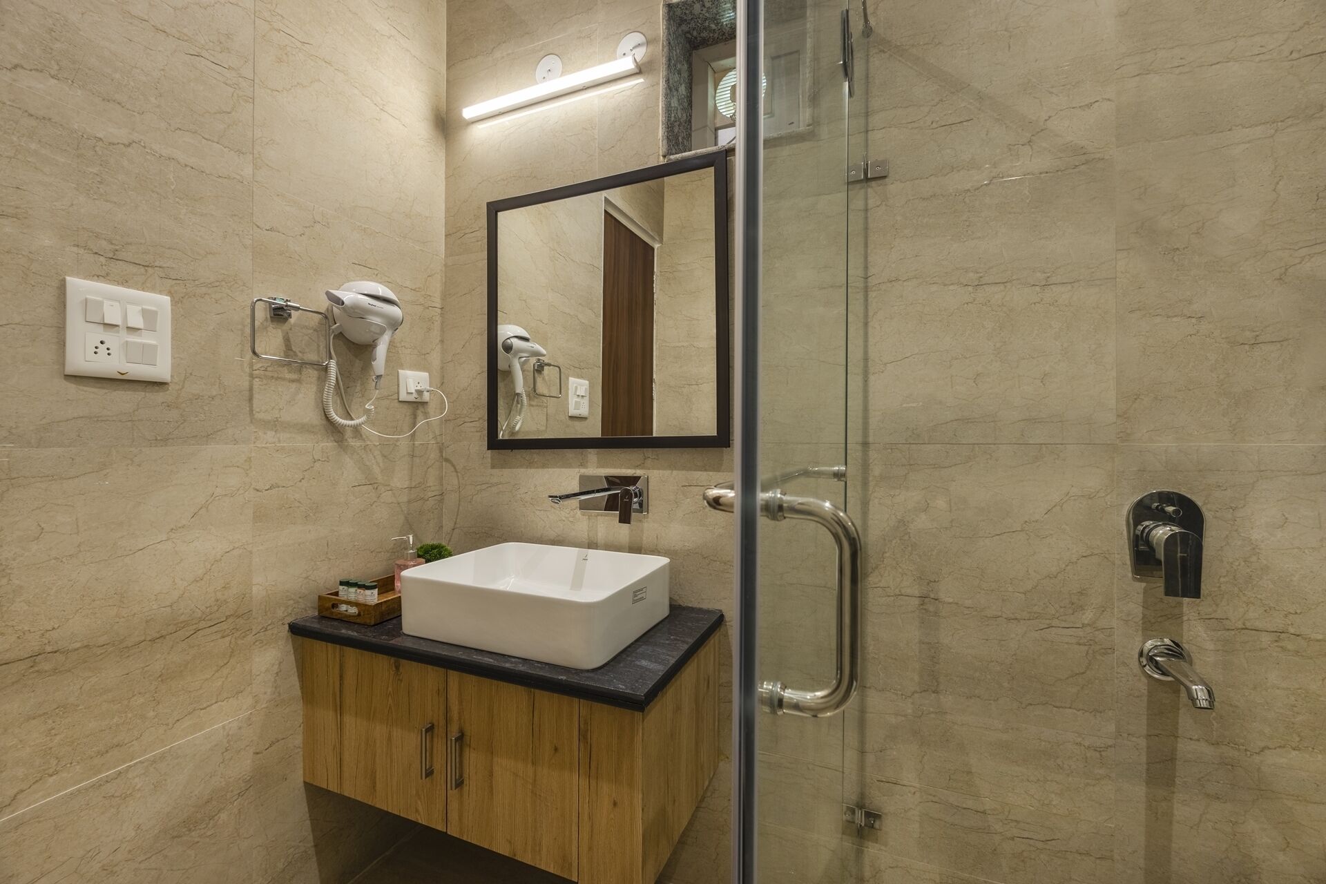 A modern bathroom with a glass shower enclosure, a white sink, and a wooden vanity.