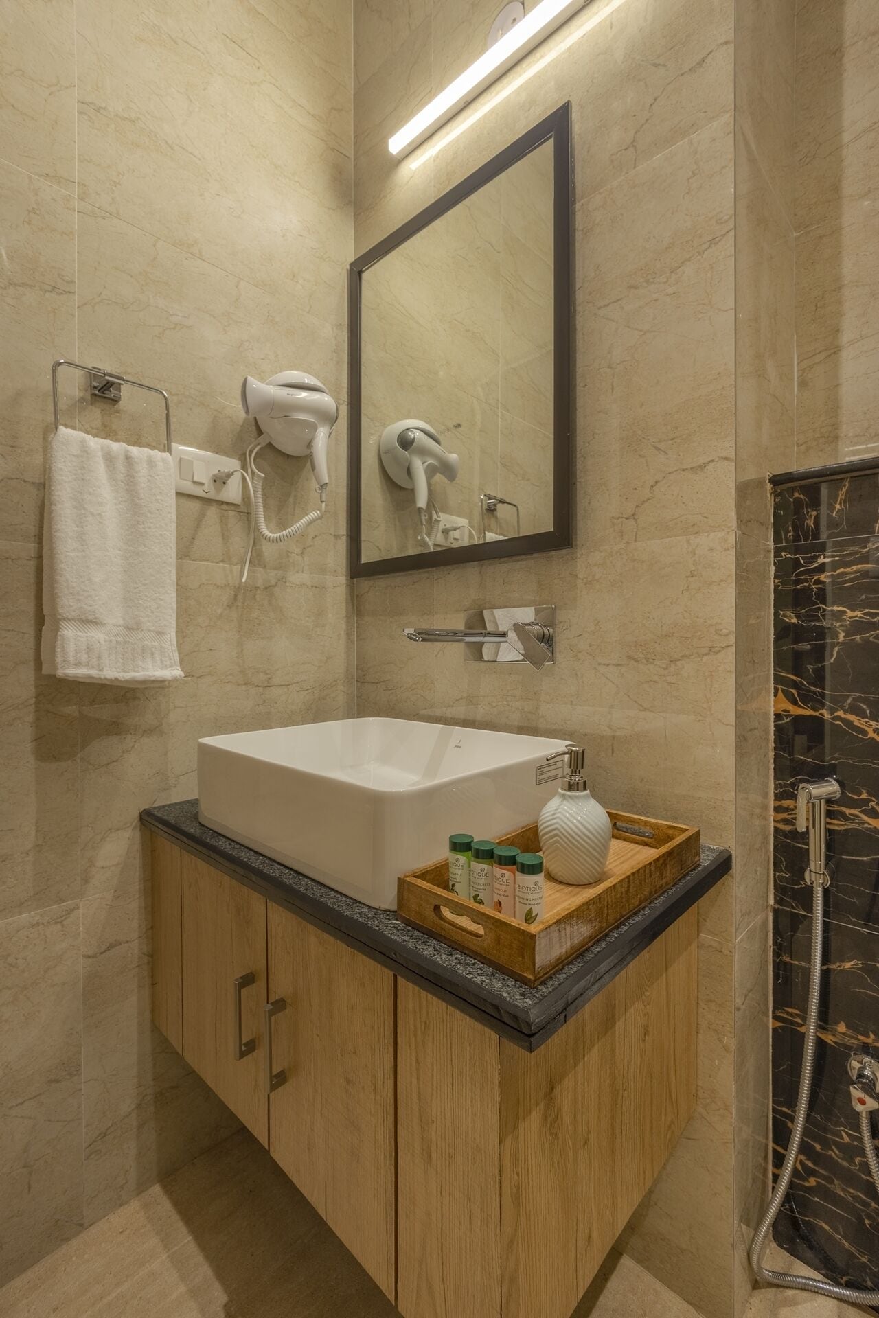 A modern bathroom with a large sink, a hairdryer, a mirror, and a shower.