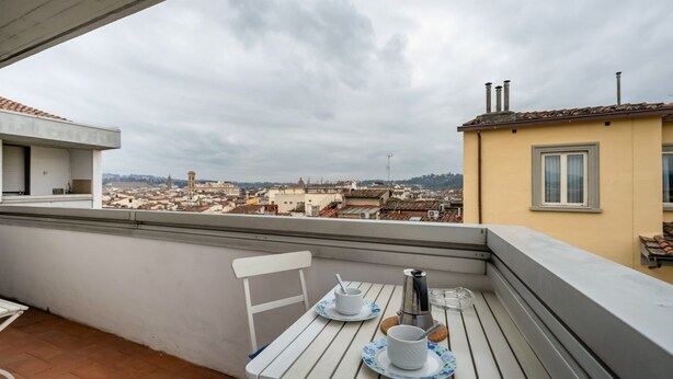 A balcony with a table set for two, overlooking a cityscape. - GuestHost - Cozy 45 sqm apartment, able to accommodate up to 4 people, located on the sixth floor of a modern building with lift.The property is located in an extremely strategic area, just 100 meters from Santa Maria Novella station, near the historic c (Florence)