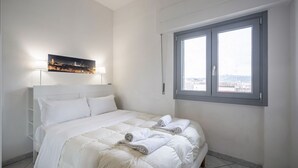 A bedroom with a bed, a window, and a cityscape view. - GuestHost - Cozy 45 sqm apartment, able to accommodate up to 4 people, located on the sixth floor of a modern building with lift.The property is located in an extremely strategic area, just 100 meters from Santa Maria Novella station, near the historic c (Florence)