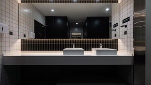 A modern bathroom with two sinks, a large mirror, and a dark tiled wall. - Hangzhou Desti Youth Park Hostel West Lake (Hangzhou)