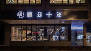 A building with a sign that reads "Hotel Ten Year" and a logo with a circular emblem. - Hangzhou Desti Youth Park Hostel West Lake (Hangzhou)