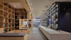 A modern library with wooden and metal shelving, a central reading area, and a long counter. - Hangzhou Desti Youth Park Hostel West Lake (Hangzhou)