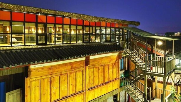 Un edificio de varios pisos con fachada de madera y sección superior roja.