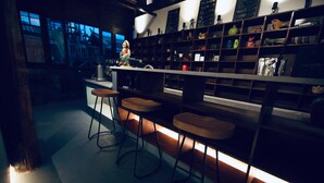 Una zona de bar con taburetes y estantes con diversos objetos.