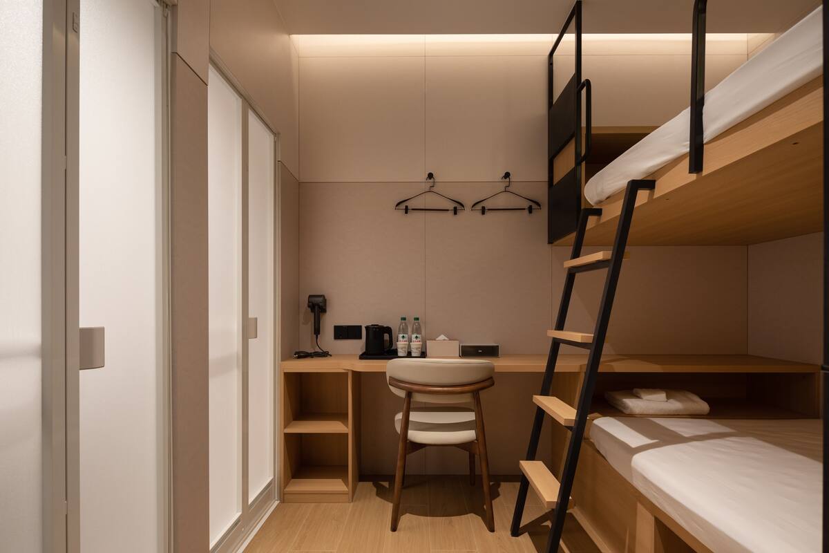 Quarto compacto com beliche, escrivaninha, cadeira e guarda-roupa.
