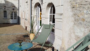 Une cour avec deux fauteuils de jardin verts et une petite table ronde, le tout entouré de gravier.