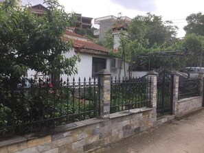 A residential area with a white building, stone wall, and black wrought iron fence. - 🏖Sunny Family Studio • 60m Walk to Beach • Parking & Garden (Skala Marion)