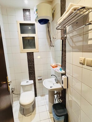 A compact bathroom with a toilet, sink, and a small window above the toilet. - Dakhnah Riyadh Saudi Arabia (Riyadh)