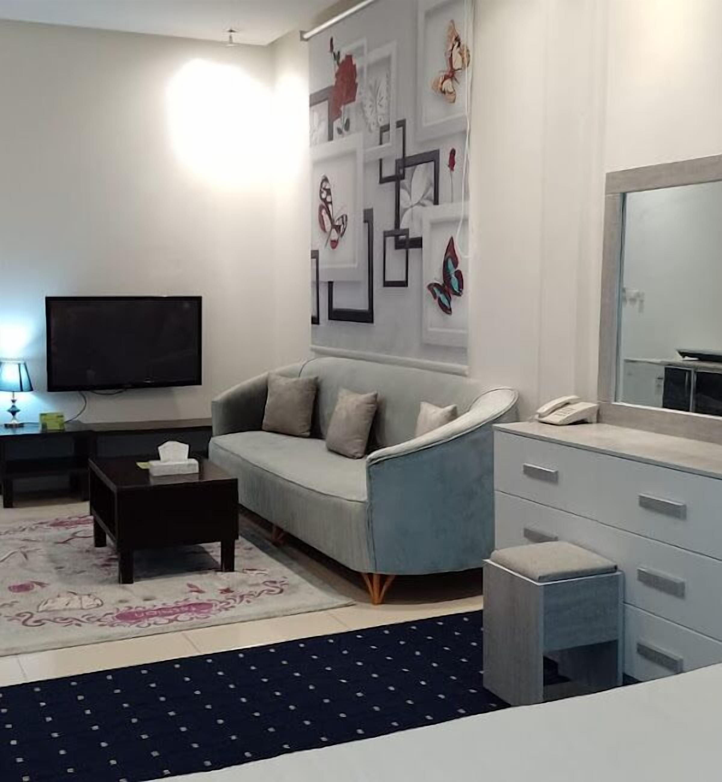 A modern living room with a grey sofa, a small coffee table, a TV, and a dresser.