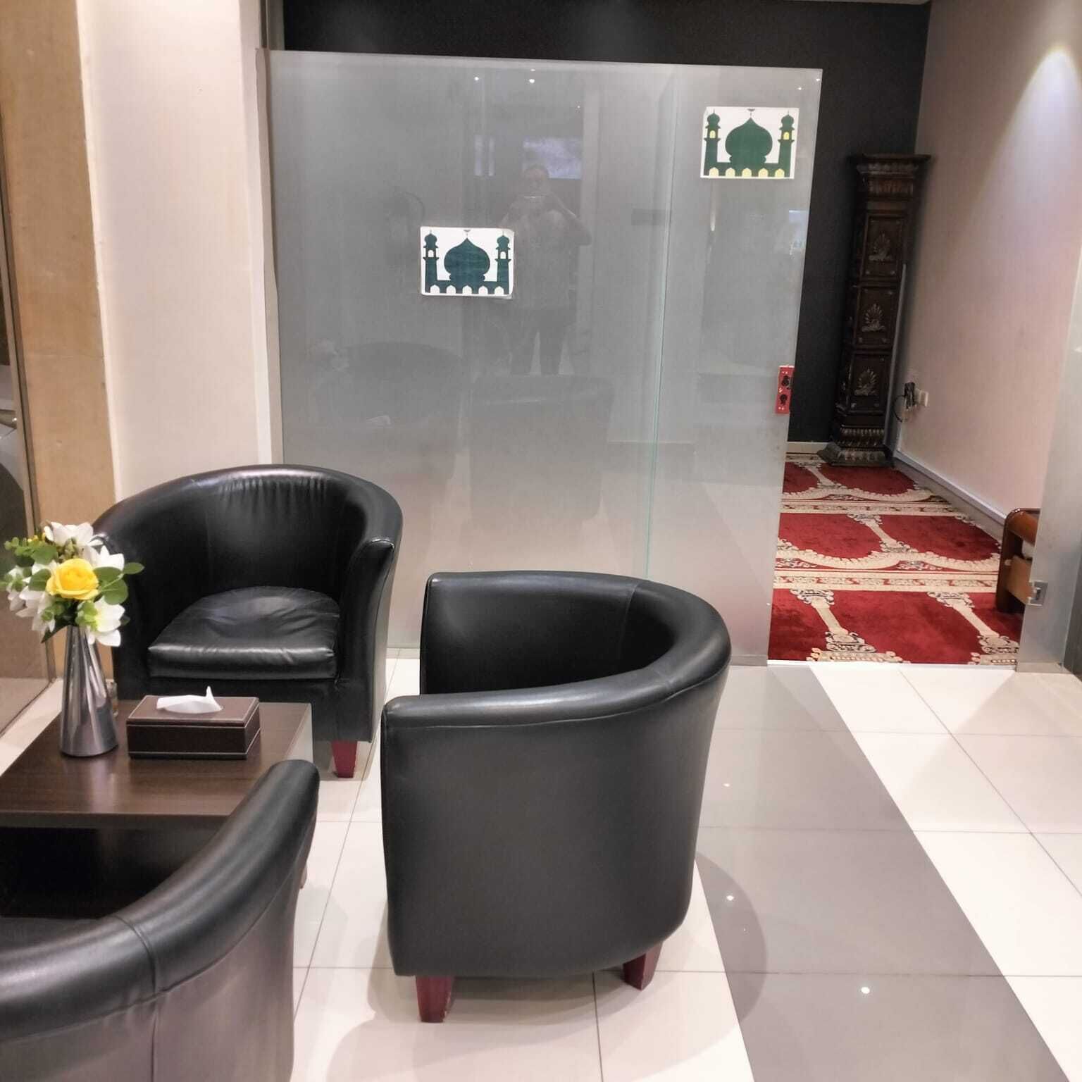 Egy előtér, melyben két fekete bőr szék, egy kis asztal virágos vázával, és egy piros szőnyeg található, mely egy ajtóhoz vezet, az ajtón pedig egy mecsetet ábrázoló matricát helyeztek el.