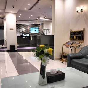 A modern lobby with a reception desk, a television screen, a flower arrangement, a tissue box, and a leather couch. - Dakhnah Riyadh Saudi Arabia (Riyadh)