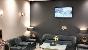 Ein modernes Wohnzimmer mit zwei schwarzen Ledersofas, einem Couchtisch und einem an der Wand befestigten Flachbildfernseher.