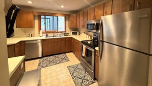 Una cocina moderna con armarios de madera, electrodomésticos de acero inoxidable y alfombras estampadas.