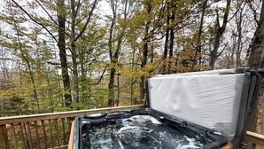 Un jacuzzi en una terraza de madera rodeado de árboles.