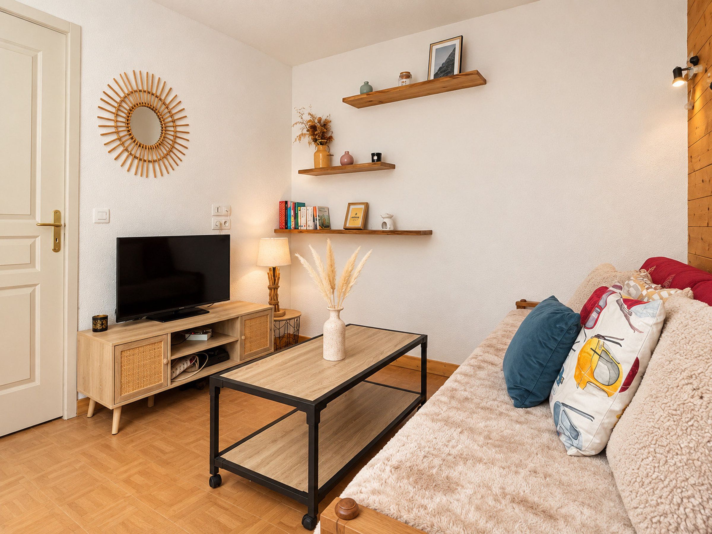 Una sala de estar con televisor, muebles de madera, una mesa de centro y un sofá con almohadones decorativos.