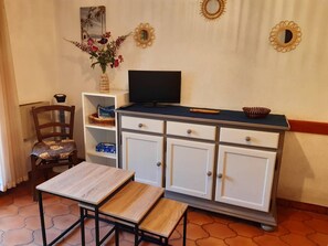 A room with a wooden table, a chair, a TV on a cabinet, and decorative items on the wall. - 2-room apartment with terrace and parking in Bormes-les-Mimosas (Bormes-les-Mimosas)