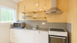 Eine moderne Küche mit weißen Schränken, einer integrierten Mikrowelle, einer Spüle aus Edelstahl und einem Einbauofen.
