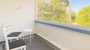 Ein kleiner Balkon mit einem weißen Stuhl und einem kleinen Rundtisch.