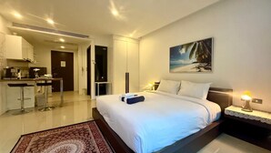 Una camera d'albergo moderna con un letto grande, un'area pranzo e una cucina.