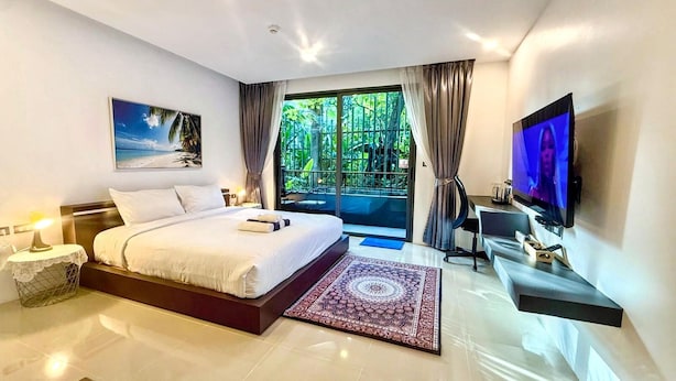 Camera da letto moderna con un letto grande, una TV, una scrivania e vista su un giardino rigoglioso.