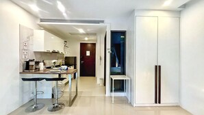 Una cucina moderna con un bancone, un armadio bianco e un piccolo angolo salotto.