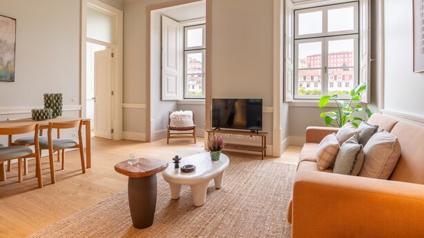 Una sala de estar con un sofá, una mesa de centro, un televisor y un comedor con sillas y una mesa.