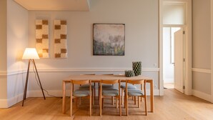 Un comedor con una mesa y sillas de madera, una lámpara de pie y un cuadro en la pared.