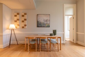 A dining area with a wooden table and chairs, a floor lamp, and a painting on the wall. - FLH Heart of Rossio Apartment V (Lisboa ciudad)