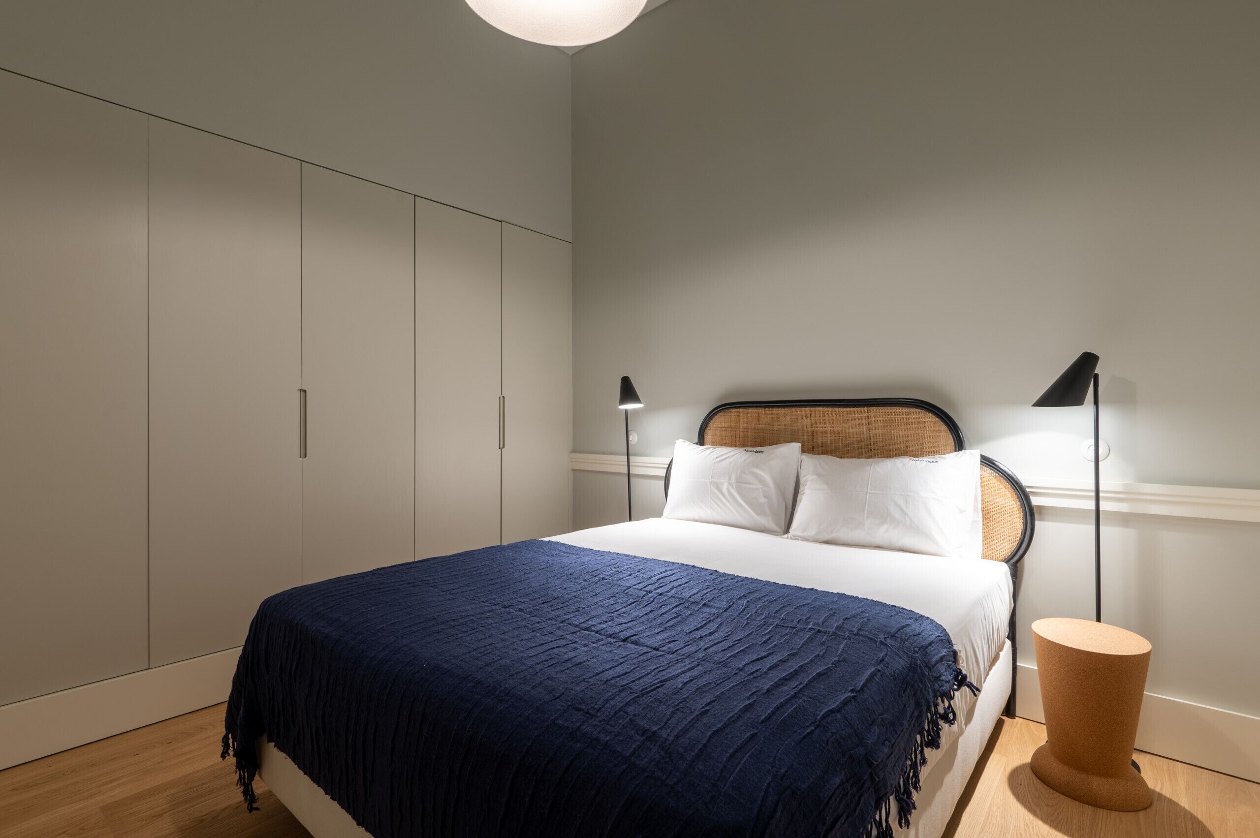 A bedroom with a bed, a wardrobe, and a nightstand with a lamp.