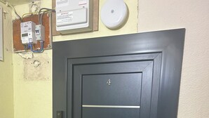 Een zwarte deur met het nummer 4, een codeerapparaat en een intercom bevestigd aan de muur.