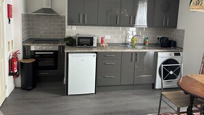 Een moderne keuken met grijze kastjes, een ingebouwde magnetron, een vaatwasser en een koffiezetapparaat.