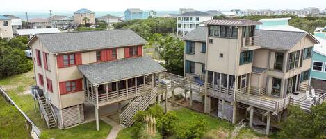 A coastal house with a two-story structure, a covered porch, and a staircase leading to the upper level.